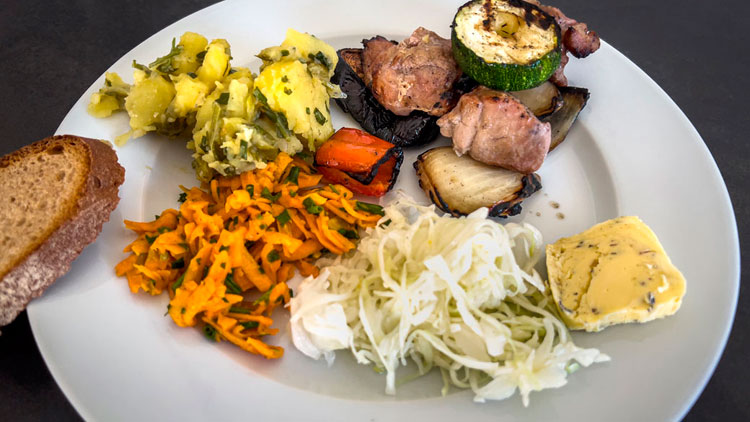 Teller mit Gegrilltem, Gemüse, Kartoffeln und Salat